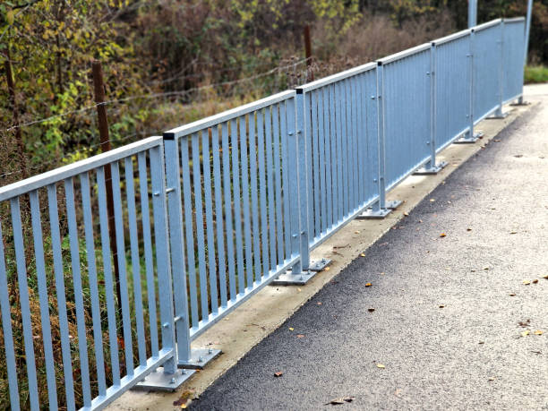 istock bridge railing with vertical fence posts anchored into the ground with four concrete screws. the railing is fixed from the side of the bridge into the concrete. 2186928985