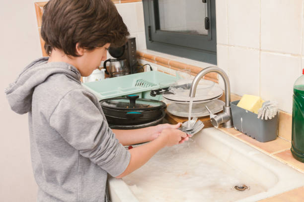 istock A young boy washes cutlery in a marble sink. 2186929148