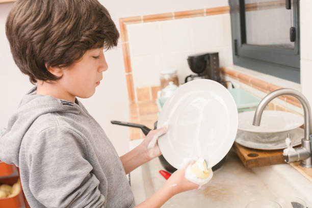 istock A young boy is washing a dirty plate in the kitchen 2186929203