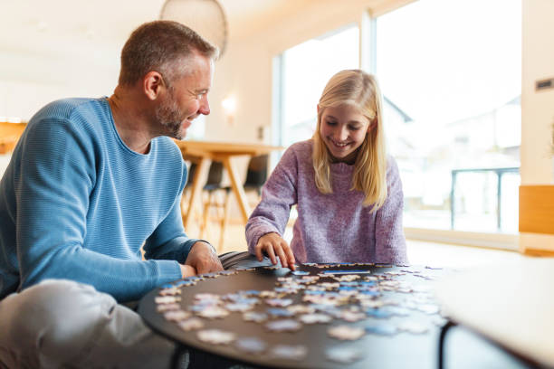 istock Father and Daughter Solving Jigsaw Puzzle at Home 2186934576