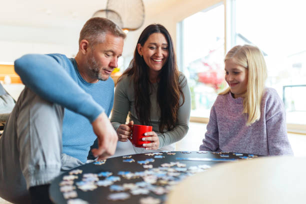 A cheerful family engages in a puzzle activity in a cozy home setting. The scene captures warm family moments, with adults and a child enjoying quality time and laughter together.