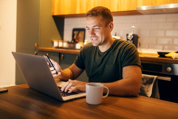 istock Smiling young man working on a laptop at cozy home at night. 2186935572