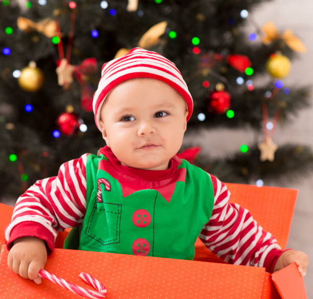 Where is gift? Curious baby elf sitting in big gift box, looking for Christmas presents, closeup