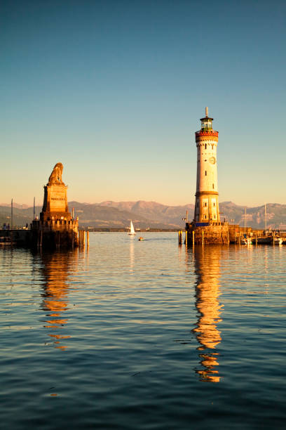Lake Constance, Lindau harbor entrance Lindau harbor entrance with monument and lighthouse at dusk lindau lighthouse stock pictures, royalty-free photos & images