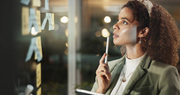 istock Night, woman or sticky notes on window for thinking, task reminders or brainstorming with tablet. Business, admin person or tech in office for schedule planning, problem solving or moodboard on glass 2186942267