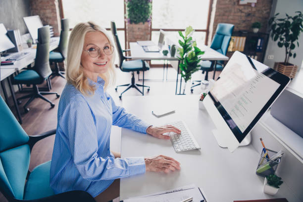 istock Mature professional woman working at modern office desk with computer in natural daylight 2186944402