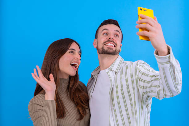 istock Couple taking selfie together with smartphone on blue background 2186946302