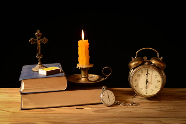 Still life, alarm clock, candlestick, candle and books on the table