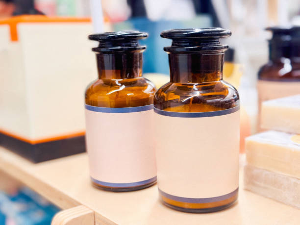 Two small glass cosmetic jars with brown lids displayed on a wooden counter.