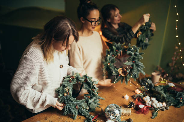 istock Happy women making Christmas wreath using natural pine branches and festive decorations. 2186955278