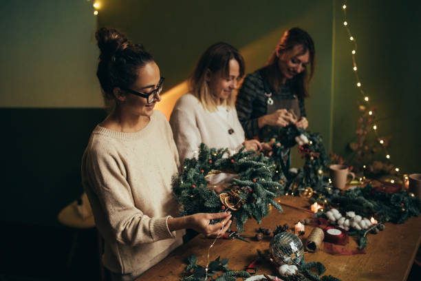 istock Happy women making Christmas wreath using natural pine branches and festive decorations. 2186955279