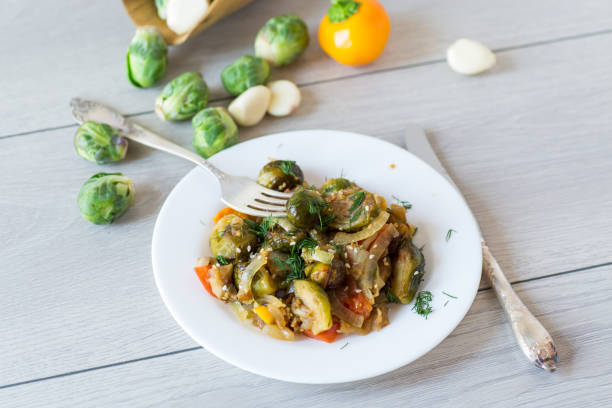 istock Brussel sprouts cooked with vegetables and spices, on a wooden table 2186956405