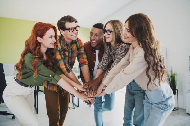 istock Portrait of five young successful colleagues pile stack handshake agreement workplace business center office indoors 2186959572