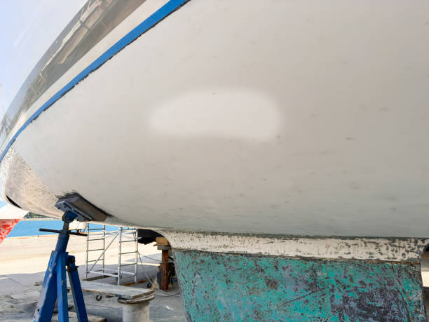 White boat on wooden supports at marina, surrounded by water and moored vessels, highlighting craftsmanship and marine environment with vibrant buildings nearby