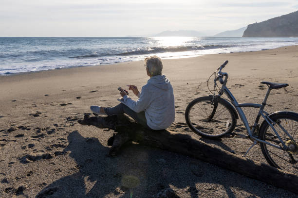 istock Mature man pauses by water's edge with bicycle 2186965127