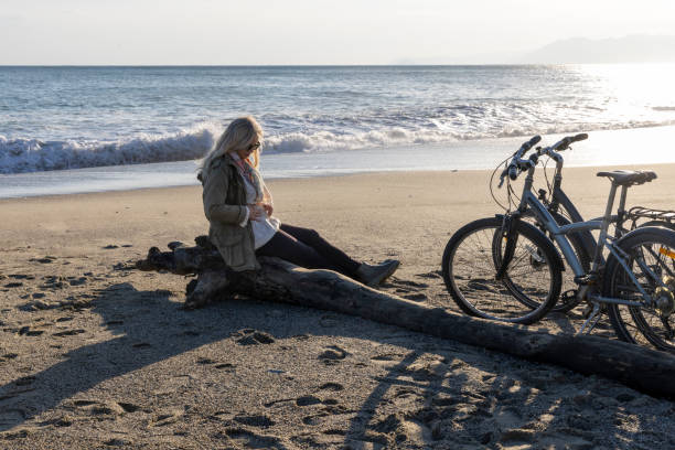 istock Mature woman pauses on beach with bicycle 2186965198
