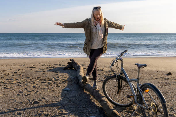 istock Mature woman  balances on log on beach 2186965200