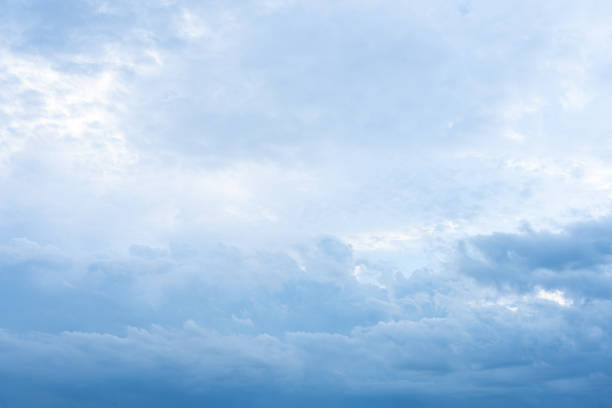 Fluffy white clouds drift across a vast expanse of clear blue sky