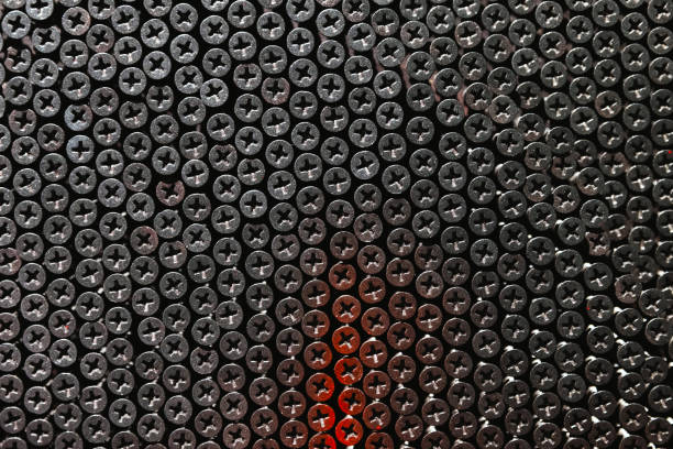 Wall fully covered with steel self-tapping screws, abstract dark industrial background photography