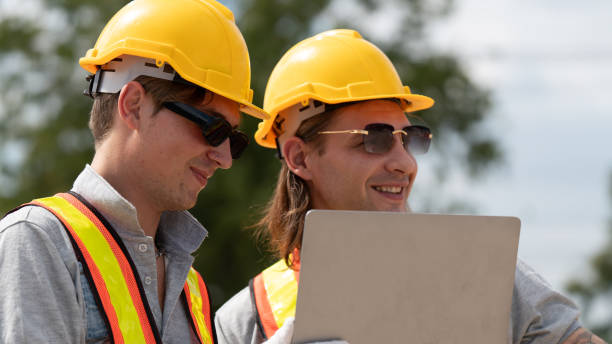 istock Caucasian white civil engineer, architect, or construction worker is wearing a safety suit while inspecting building construction on site and verifying blueprints or drawing plans. 2186971668