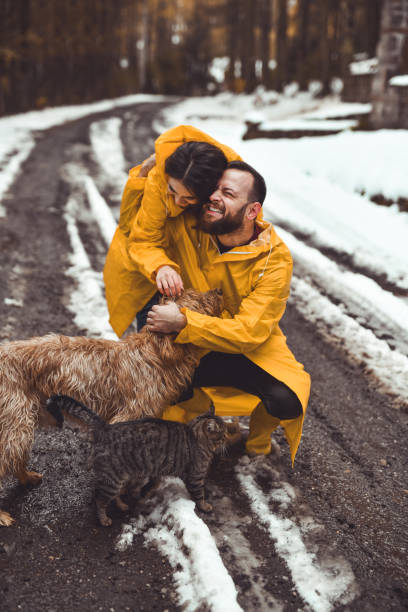 istock Lovely Couple Hugging And Embracing Their Pets While Going on Morning Walk in Snowy Forest 2186972994