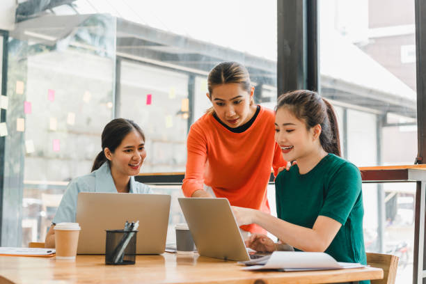 istock Collaborative women working together in modern office space, sharing ideas and engaging with laptops. Their expressions reflect enthusiasm and teamwork 2186974442
