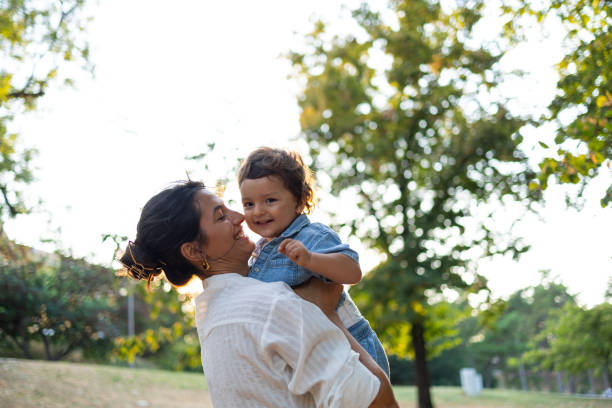 istock Mother affectionately holding her happy child in a sunny park 2186975404