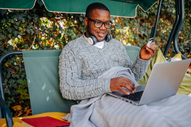 istock Young man spending time at home back yard on beautiful sunny day in Autumn using laptop 2186977903
