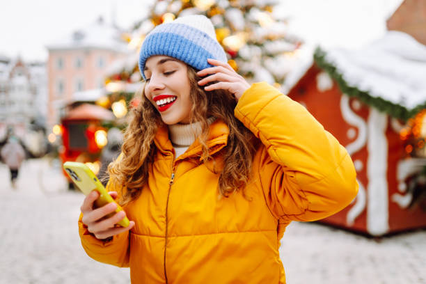 Smiling redhead woman wearing warm clothing and relaxing in the city during Christmastime
