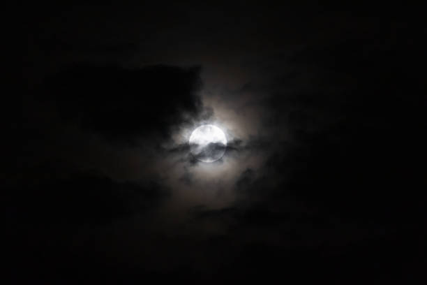 A captivating view of the moon obscured by dark clouds at night, creating a mysterious and serene atmosphere.