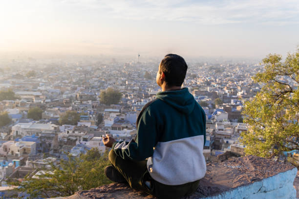 istock man meditating at mountain top with city view at sunrise 2186978607