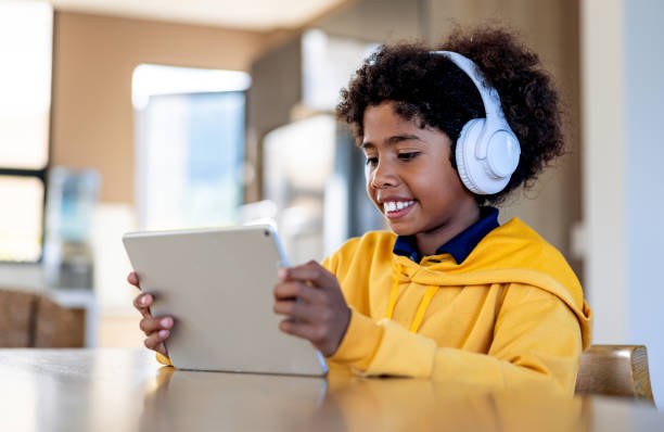 istock Happy boy playing on a digital tablet at home while using headphones 2186978749