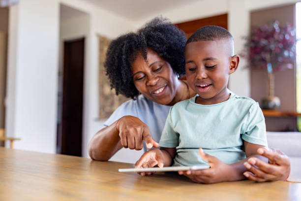 Grandmother babysitting her grandson and using a digital tablet for entertainment