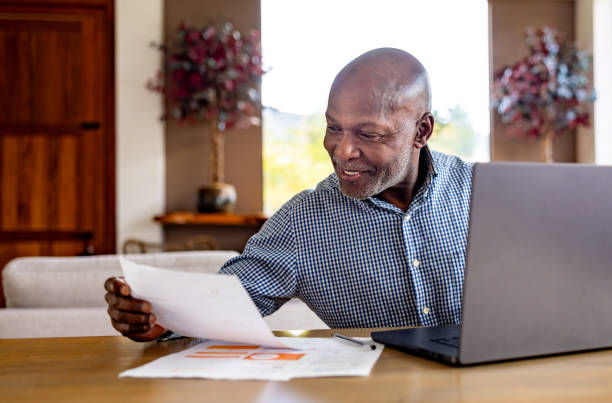 istock Happy mature man paying bills online using his laptop 2186978791