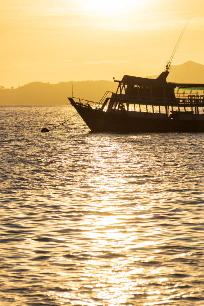 A tranquil sunset scene featuring a silhouette of a boat on shimmering water, creating a serene atmosphere.