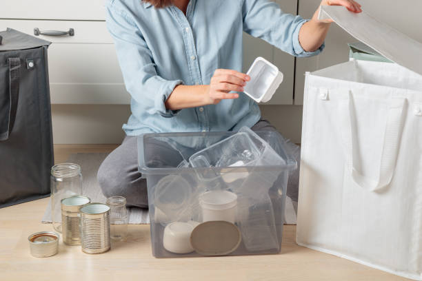 istock A young half-Asian woman sits on the floor in kitchen, methodically sorting recyclables into separate bags. She separates plastic materials, preparing them for proper recycling drop-offs 2186983488