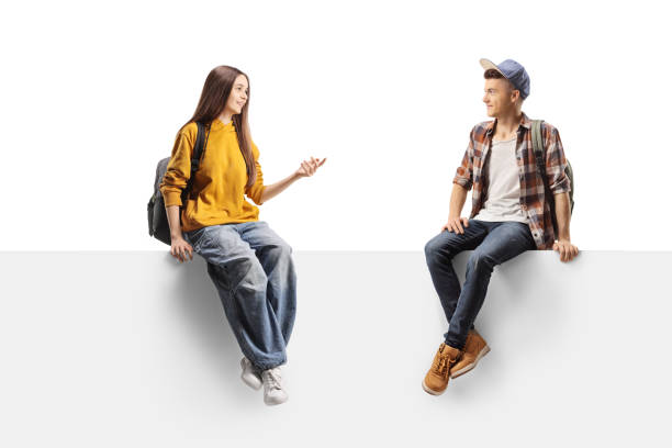 istock Teenagers sitting on a white wall and talking 2186985266