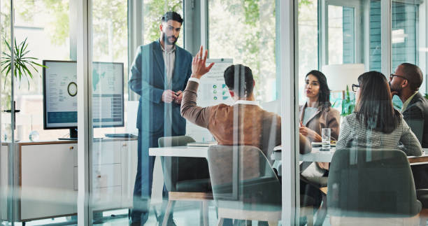 istock Business people, meeting and raised hand with question for presentation, analytics or engagement at office. Group, employees and worker with answer, solution or idea for company growth in boardroom 2186986014