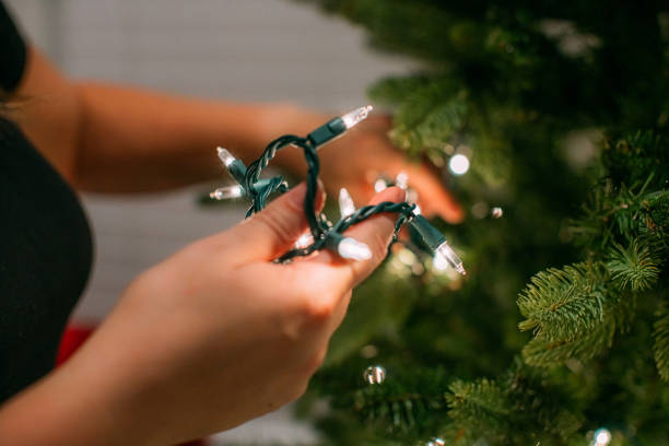 istock Caucasian Woman's Hands holding Christmas Lights while Decorating an Artificial Tree 2186986913