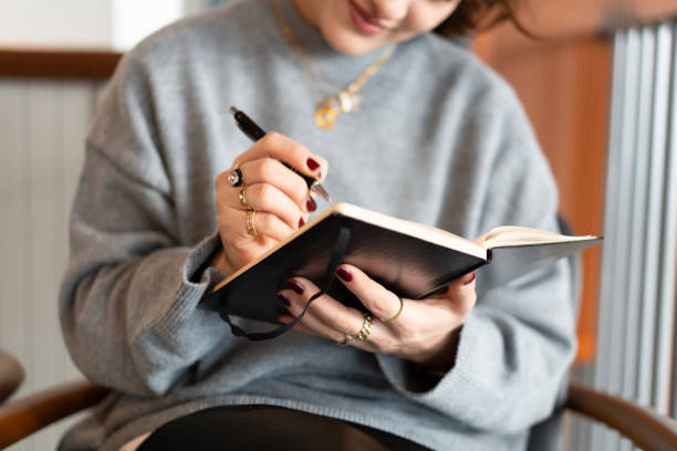 Woman writing notes in notebook at home or office