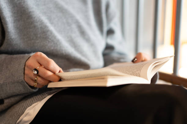 istock Woman sitting and reading a book, turning a page 2186990598