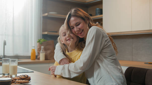 istock Mother and little daughter cuddle hold hands dancing sitting at table in kitchen breakfast loving mom dance with child girl hugging embracing kid enjoy tender family bonding cuddling. Happy motherhood 2186990623
