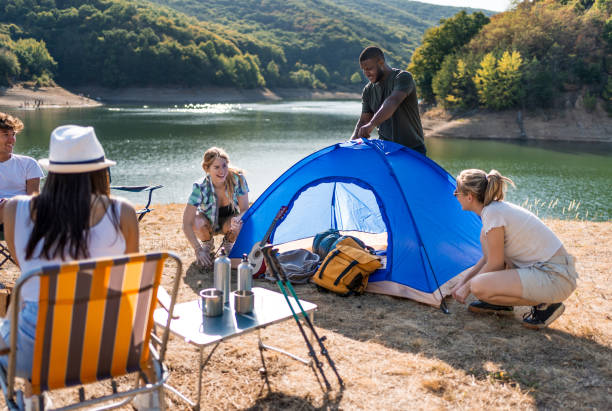 istock Young friends setting up a tent by the lake 2186990847
