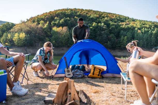 istock Young friends setting up a tent by the lake 2186990953