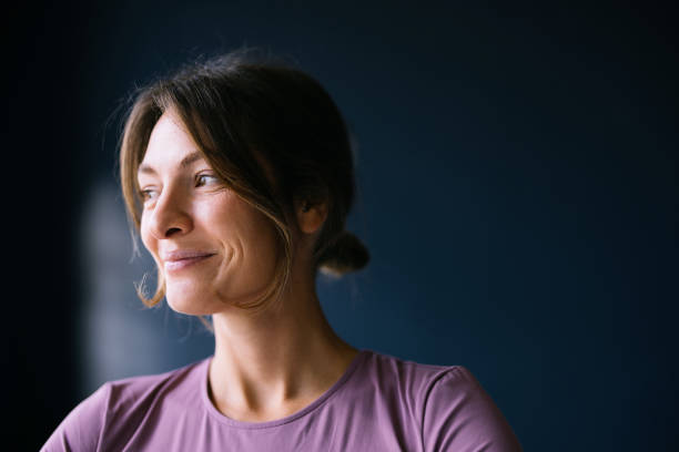 Confident Woman Smiling in Natural Light Against Dark Background