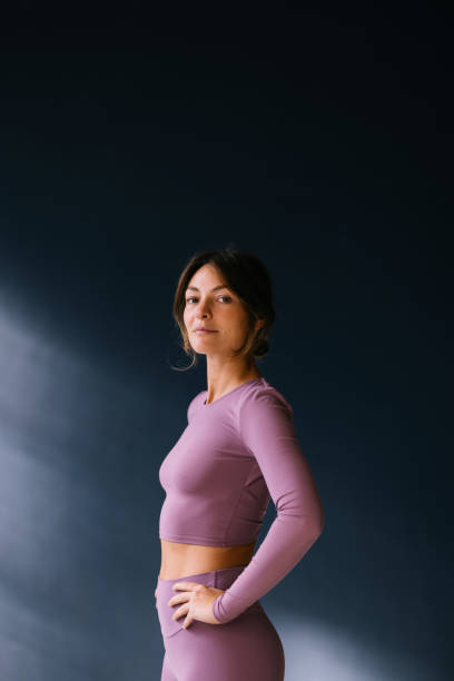 istock Confident Woman in Lilac Activewear Posing Against Dark Background 2186993442