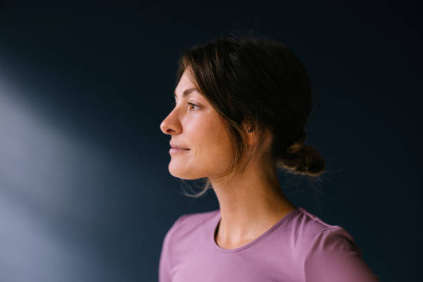 istock Contemplative Woman Posing in Natural Light Against Dark Background 2186993447