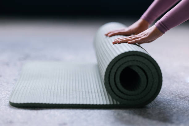 istock Close-Up of Hands Rolling a Yoga Mat on the Floor 2186993466
