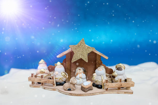 White nativity figurines of Joseph, Mary, and baby Jesus on blue defocused background with copy space. Horizontal image would be good for Christian or religious Christmas use.