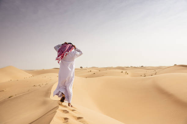 istock arabic man walking in the desert 2186997124